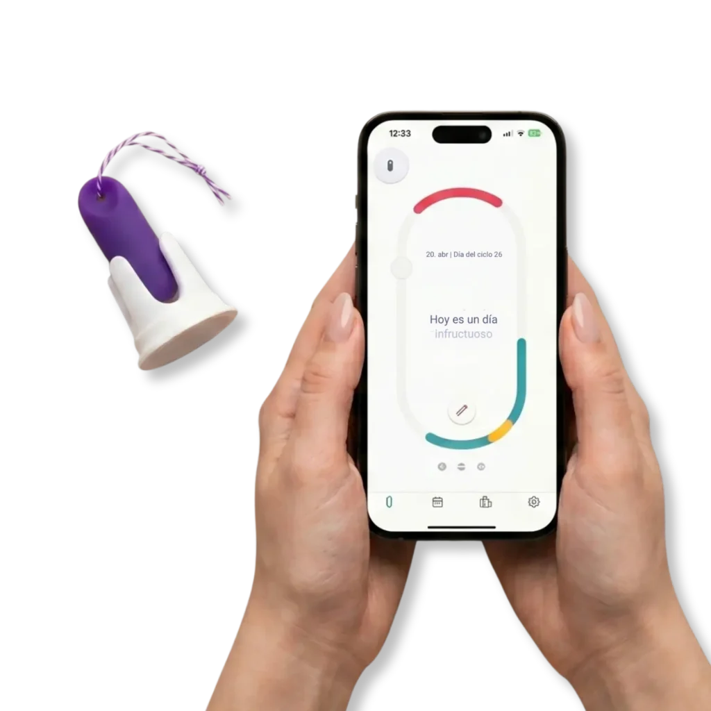 Dos manos sostienen un smartphone con la aplicación trackle, que muestra el estado del ciclo «Hoy es un día infértil». A la izquierda, se ve el sensor de temperatura morado de trackle en su soporte blanco, sobre un fondo de color morado claro.